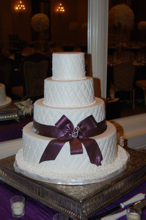 This is a four tiered round cake covered in white fondant with a white 